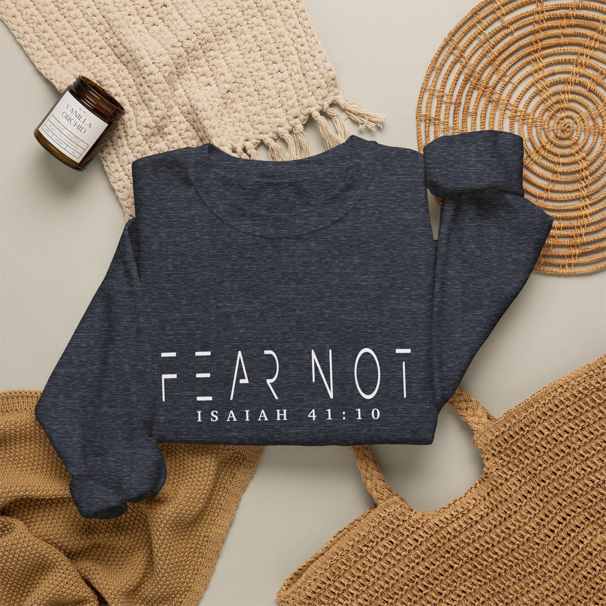 Crown N Thread navy crewneck sweatshirt with Fear Not Isaiah 41:10 text, styled with a candle and woven accessories.