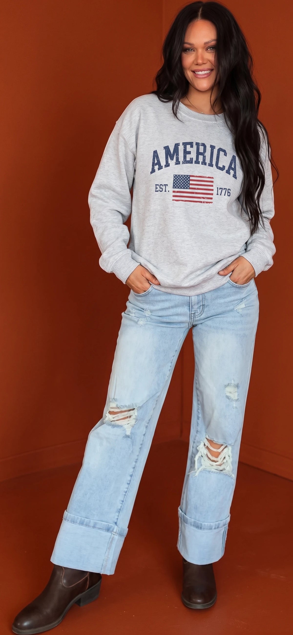 Crown N Thread grey crewneck sweatshirt with vintage America 1776 print worn by a woman with distressed light jeans
