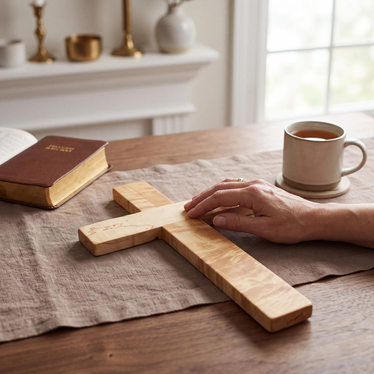 Crown N Thread handcrafted wooden wall cross with natural grain patterns resting on a table next to a Bible and mug.