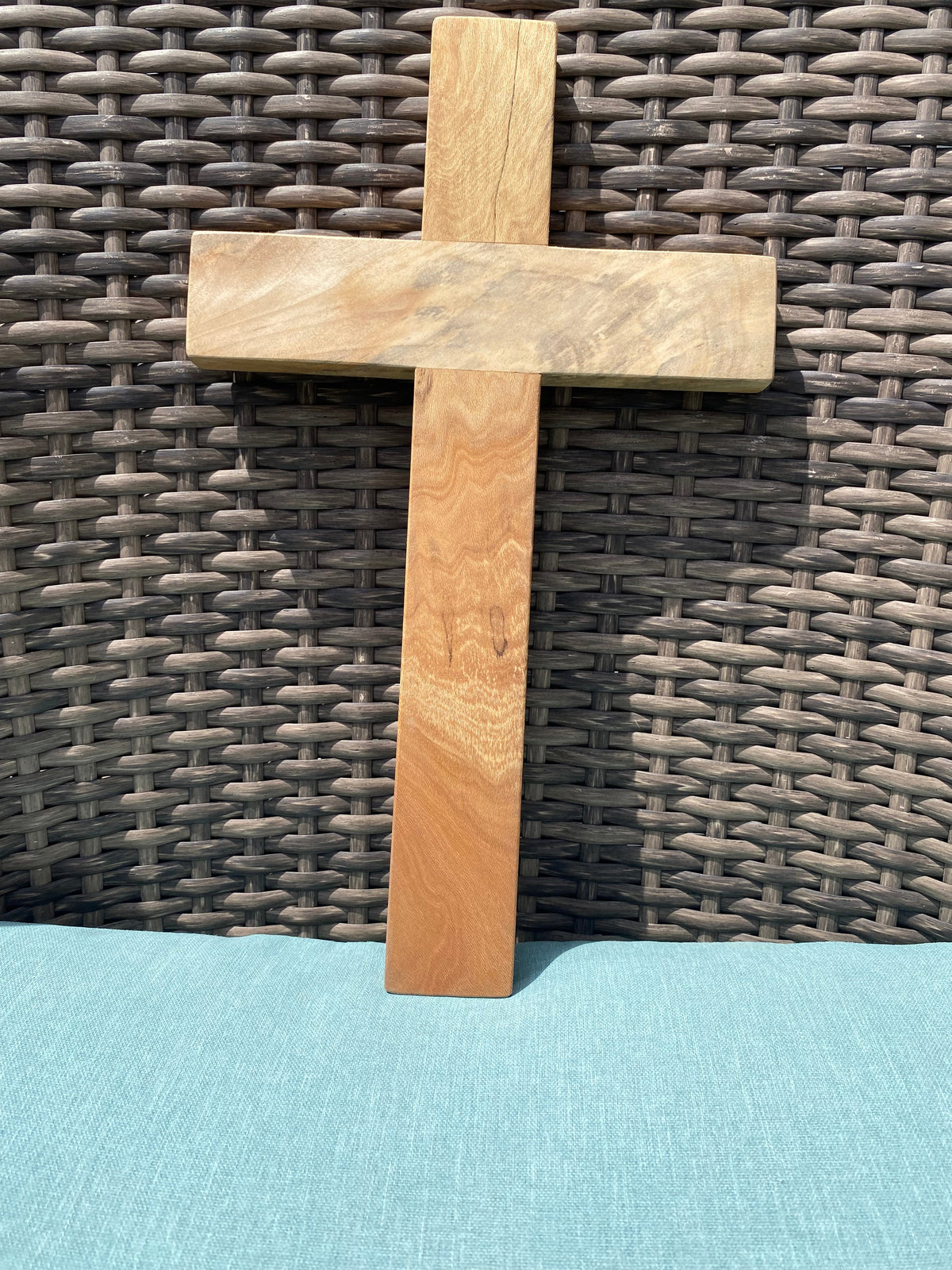 Crown N Thread handcrafted wooden wall hanging cross with natural wood grain finish on a woven background