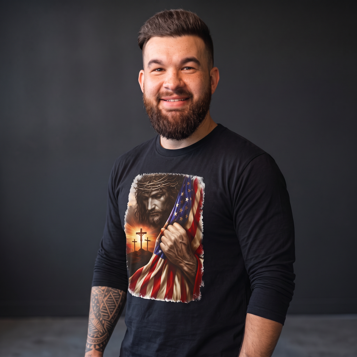 A bearded man wearing a Crown N Thread black long-sleeve tee featuring a graphic of Jesus, crosses, and a US flag.
