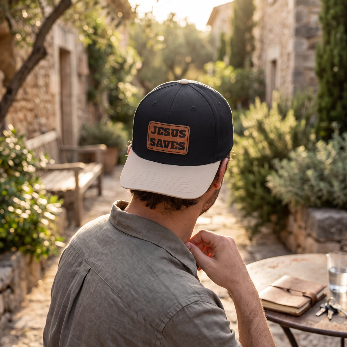 Crown N Thread baseball cap with a light brown vegan leather patch reading Jesus Saves, worn by a man outdoors.