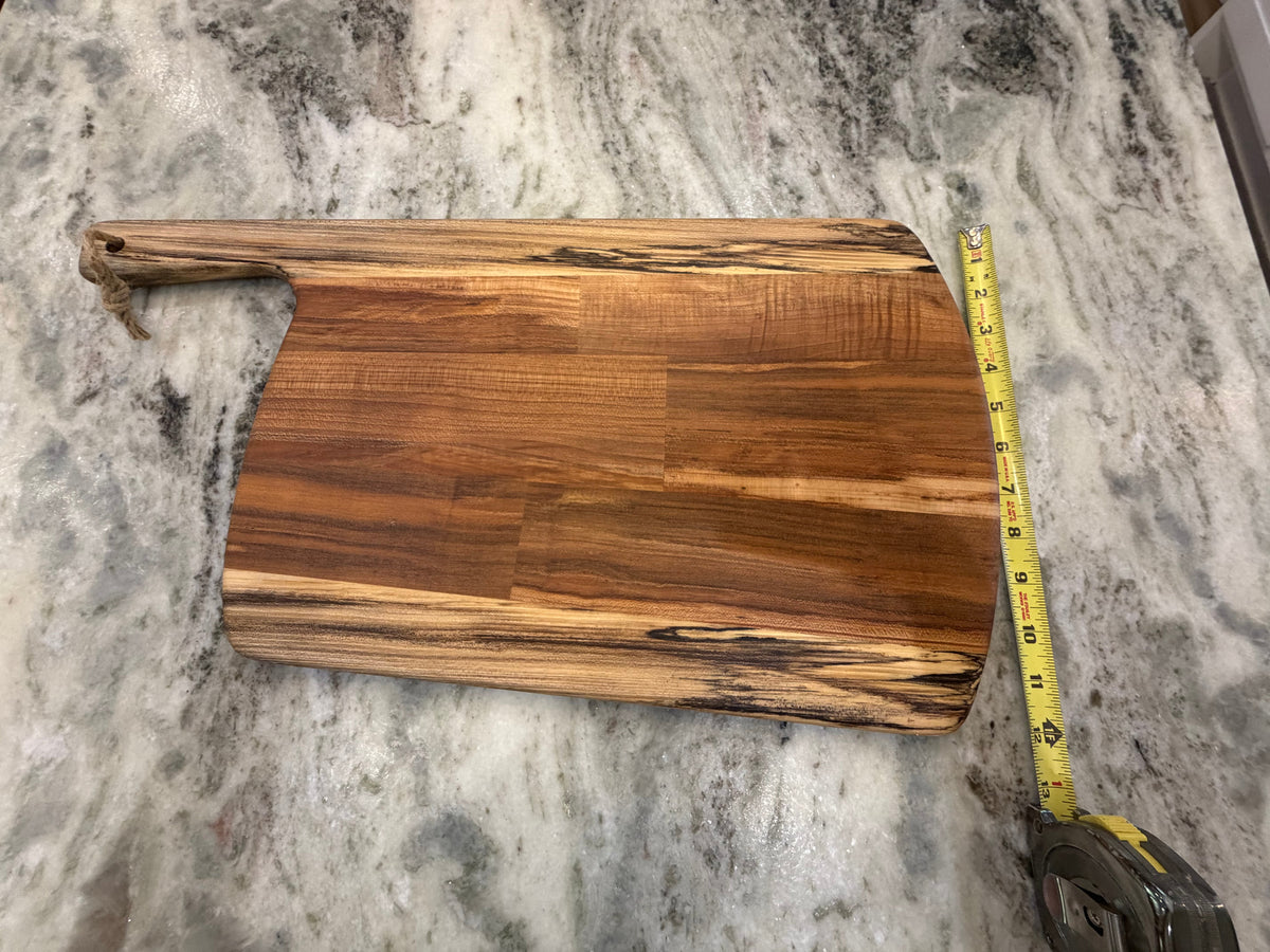 Crown N Thread handmade oiled wooden charcuterie board with natural grain patterns and a side handle on marble counter