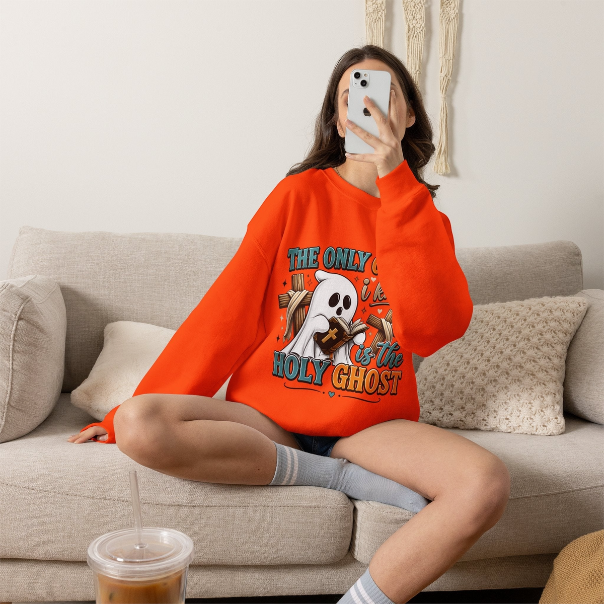 Crown N Thread bright orange crewneck sweatshirt featuring a cute ghost graphic reading a Bible on a cozy sofa.